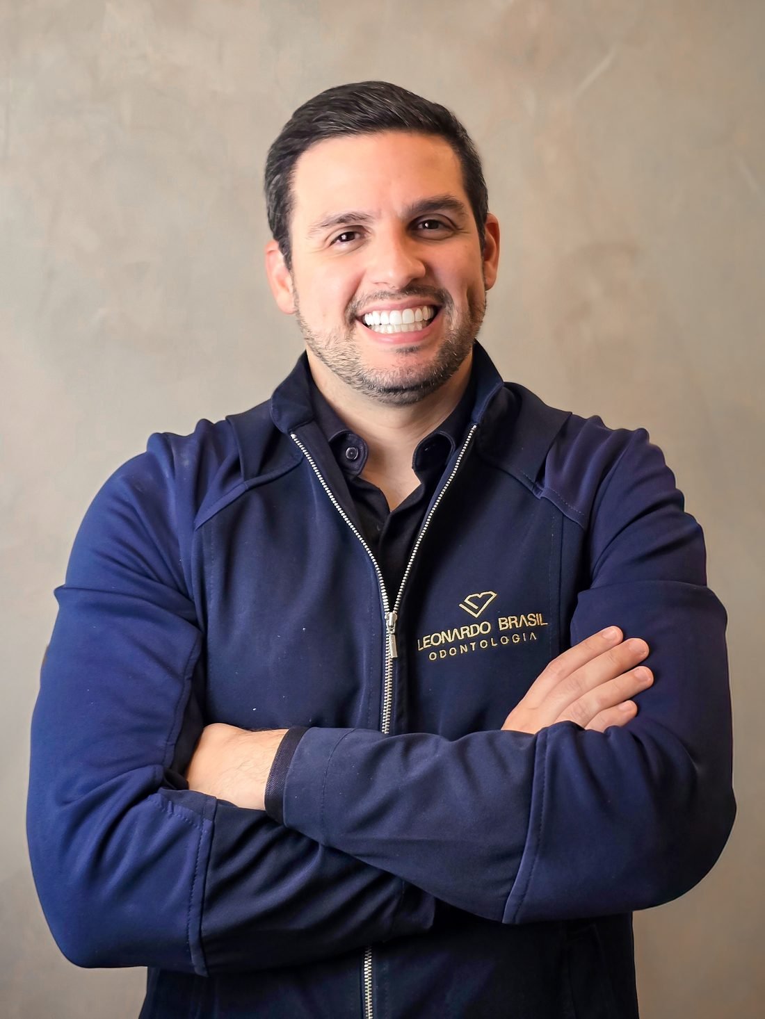 Dr. Leonardo Brasil, cirurgião-dentista em Recife, sorrindo com o uniforme da clínica Leonardo Brasil Odontologia